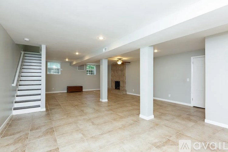 A spacious room with a staircase on the left and a door on the right.
