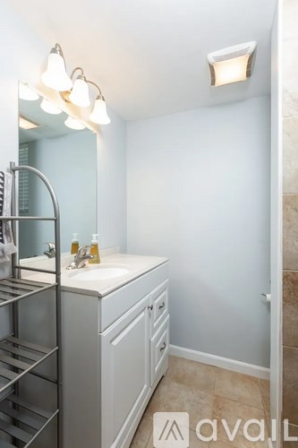 A bathroom with a sink, mirror, and light fixture.