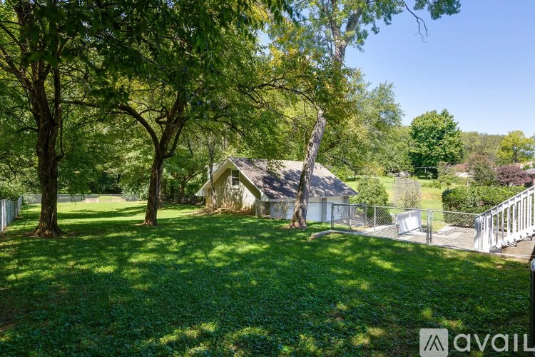 A house is surrounded by a green lawn and trees.
