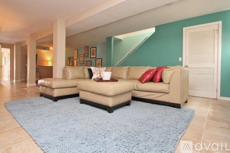 A living room with a blue rug and a beige couch.