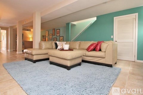 A living room with a blue rug and a beige couch.