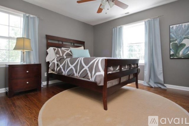 A bedroom with a bed, nightstand, and a rug.