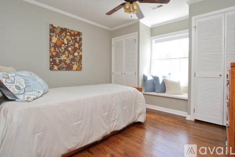 A bedroom with a bed, a window with a view of the backyard, and a ceiling fan.