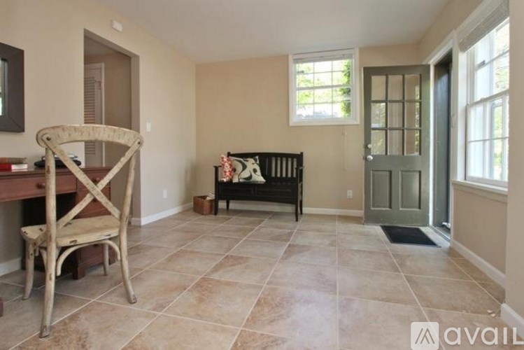 A room with a wooden chair and a bench with a black cushion.
