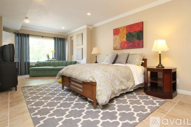 A bedroom with a large bed, a green sofa, and a painting on the wall.