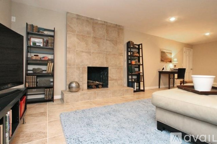 A living room with a fireplace and a blue rug.