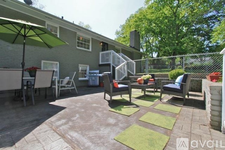 A patio with a table and chairs and a green umbrella.