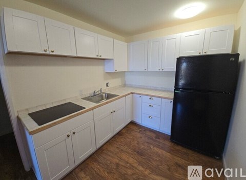 A kitchen with white cabinets and a black fridge.