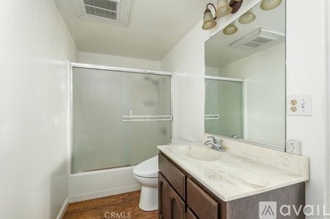A bathroom with a toilet, sink, and mirror.