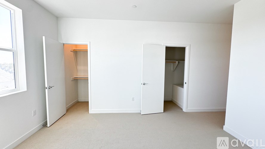A white room with two open doors and a carpeted floor.