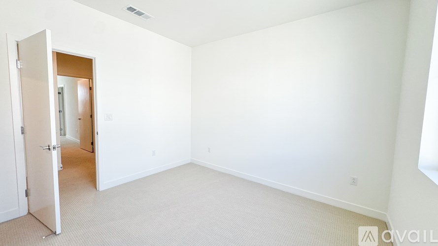 A room with a carpeted floor and a door leading to another room.