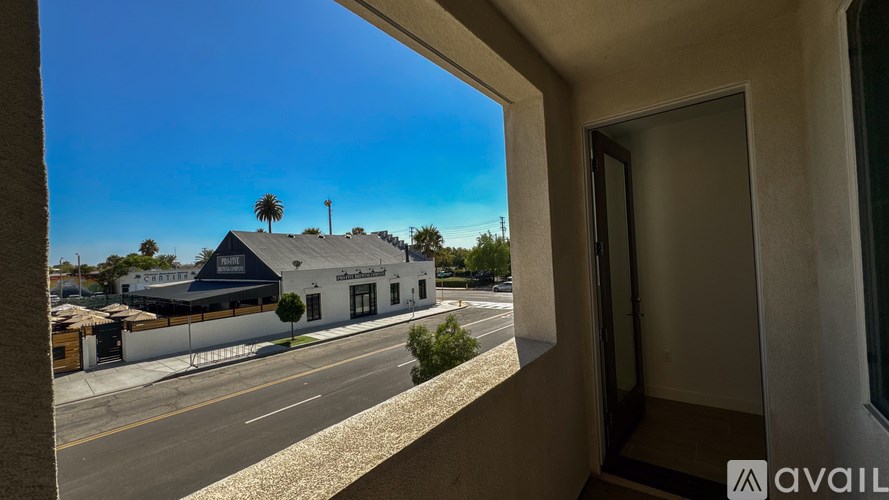 A view from a window looking out at a street with a building and palm trees.