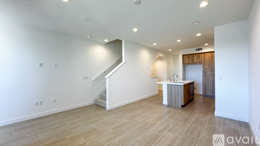 A spacious room with a staircase and a kitchenette.