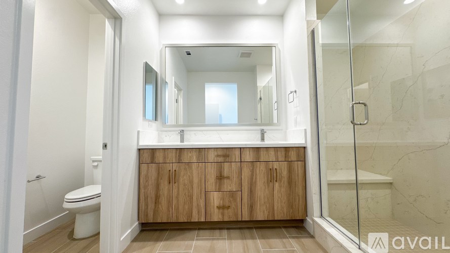 A bathroom with a toilet, sink, and wooden cabinets.