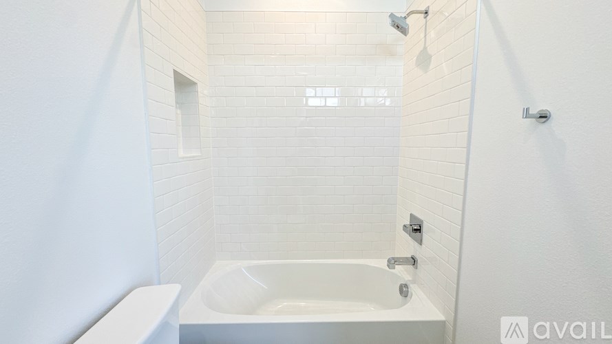 A white bathroom with a tub, toilet, and shower.
