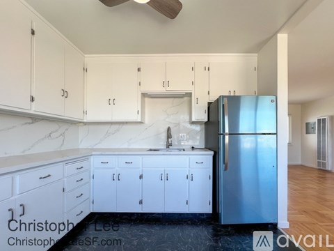 A kitchen with white cabinets and a stainless steel refrigerator.