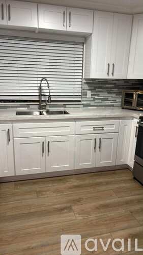 A kitchen with white cabinets and a wooden floor.