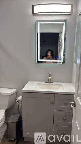 A bathroom with a toilet, sink, and mirror.