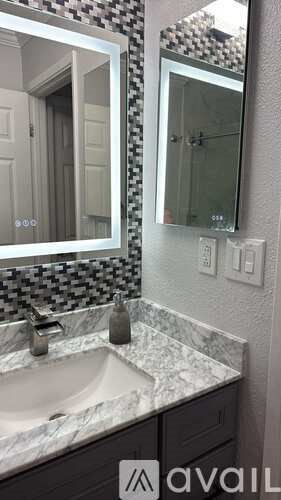 A bathroom with a marble countertop and a mirror above the sink.