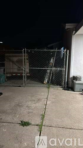 A dark alley with a chain link fence and a gate closed.