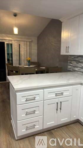A kitchen with white cabinets and a marble countertop.
