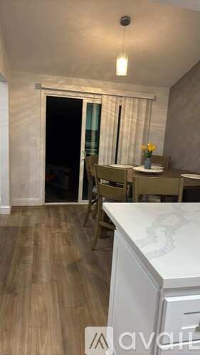 A kitchen with a table and chairs in front of a sliding glass door.