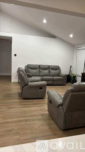 A living room with a grey sofa set and a wooden floor.
