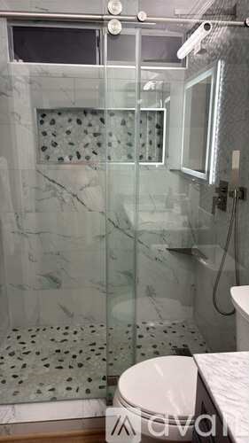 A bathroom with a glass shower door and a toilet.