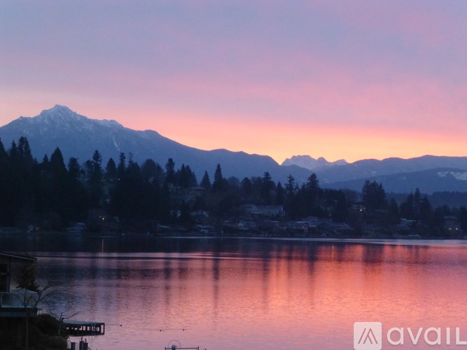A mountain range is reflected in the water in front of a house.