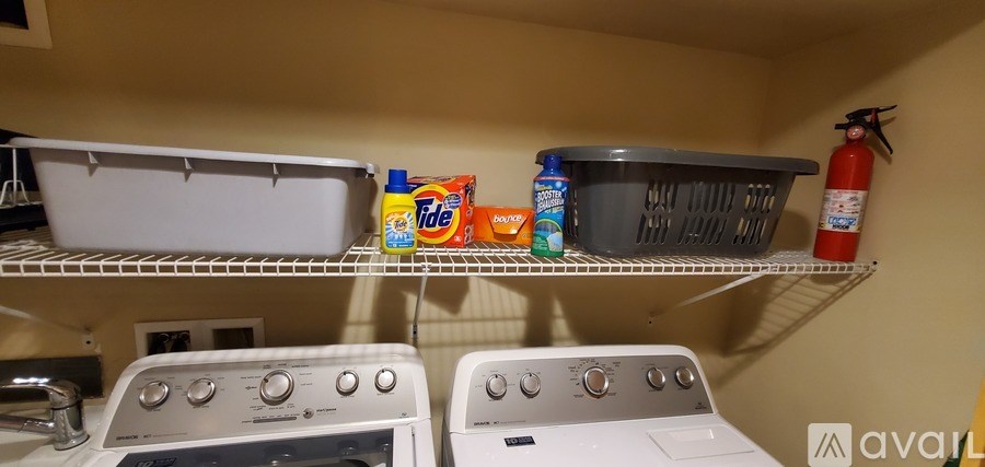 A laundry room with two washing machines and a shelf with cleaning supplies.