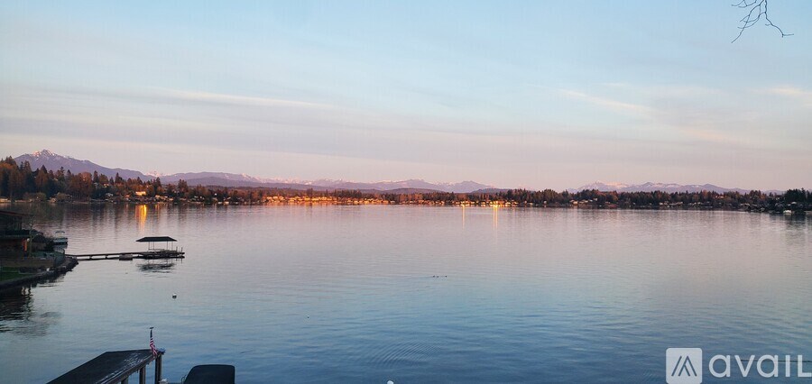 A serene lake with boats and mountains in the distance during sunset.