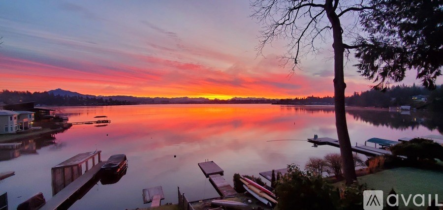 A serene lake with boats docked at the pier during sunset.
