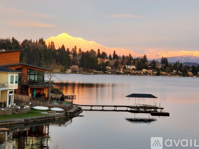 A serene lakeside scene with a mountain in the background and a house on the left.
