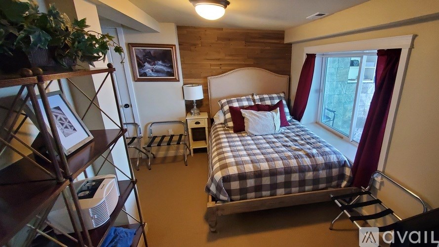 A bedroom with a bed, nightstand, and a window with red curtains.