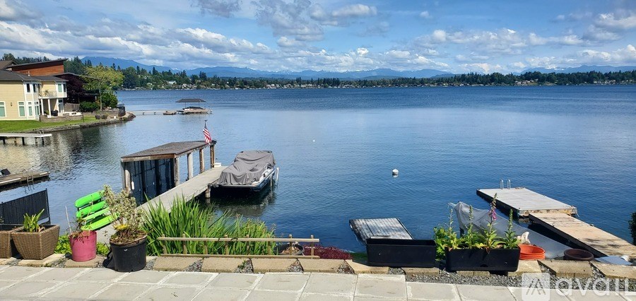 A lake with boats docked at a pier and a house in the background.