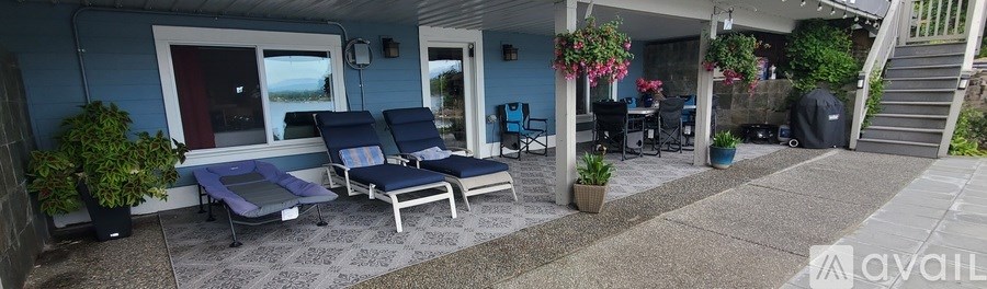 A blue house with a patio and a couple of chairs.