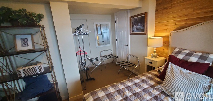 A bedroom with a bed, a nightstand, and a chair.