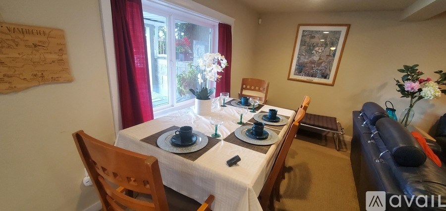 A dining room with a table set for two and a couch.