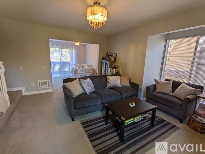 A living room with a grey couch, a coffee table, and a chandelier.