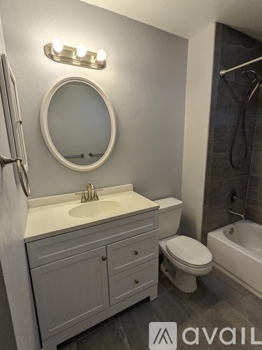 A bathroom with a white sink and a round mirror above it.