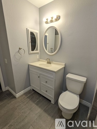 A bathroom with a toilet, sink, and mirror.