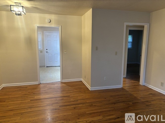 A room with wooden floors and two doors, one of which is open.