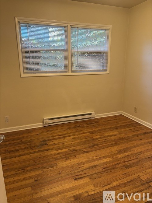 A room with wooden floors and a window with blinds.