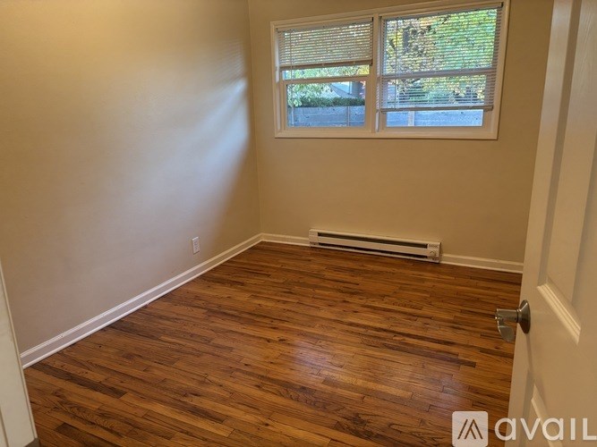 A room with wooden flooring and a window with blinds.