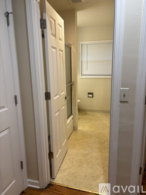 A hallway with a white door and a window.