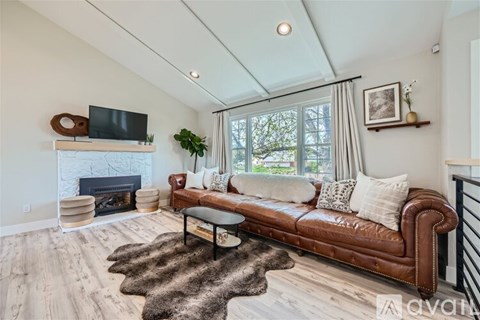 A living room with a brown leather couch and a fireplace.