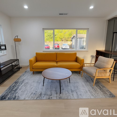 A living room with a yellow sofa, a round table, and a grey rug.