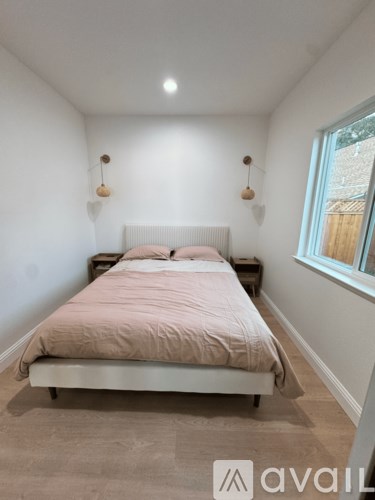 A bedroom with a bed, two lamps, and a window.