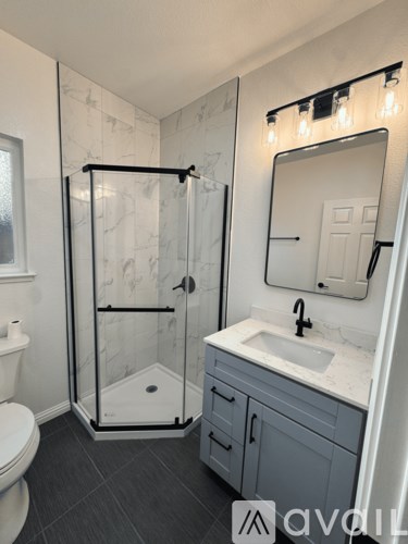 A bathroom with a marble shower and a white toilet.