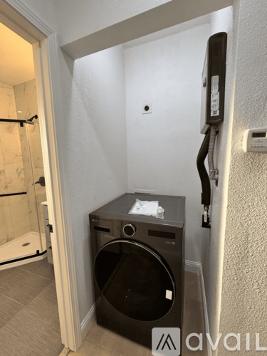 A black washing machine in a small room with a towel rack on the wall.